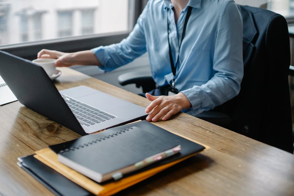 Woman writing cover letter on laptop with coffee in workspace