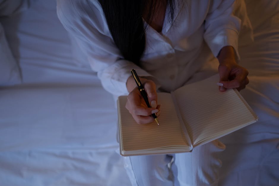 Person writing AI journal prompts responses in a notebook on a bed