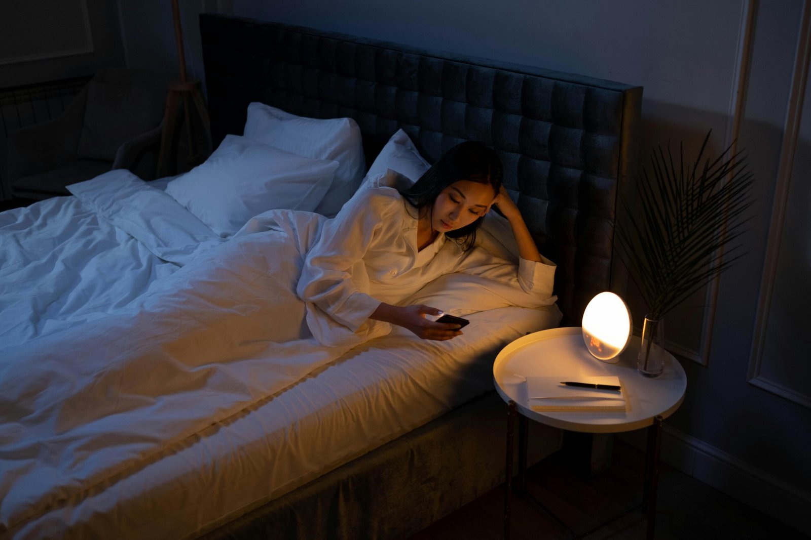 Woman on bed using phone illustrating habits that AI sleep tracker can identify