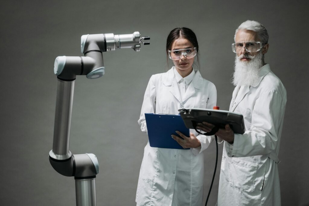 Two scientists in lab coats analyzing a robotic arm in a laboratory setting.