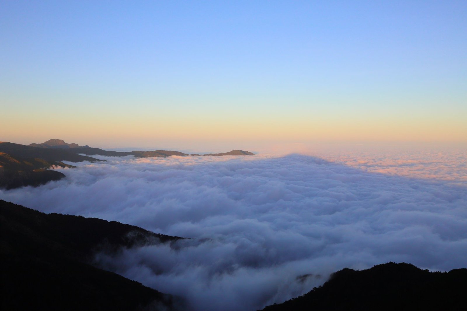 Mountain peaks above a sea of clouds, a metaphor for the AI frontier Claude Opus 5 gets close to