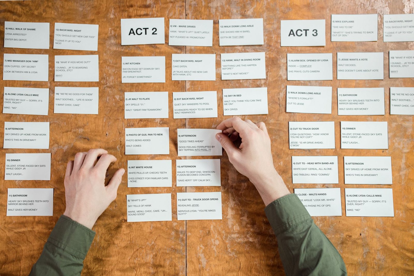 Hands arranging screenplay cards, an idea on paper before it becomes a visual