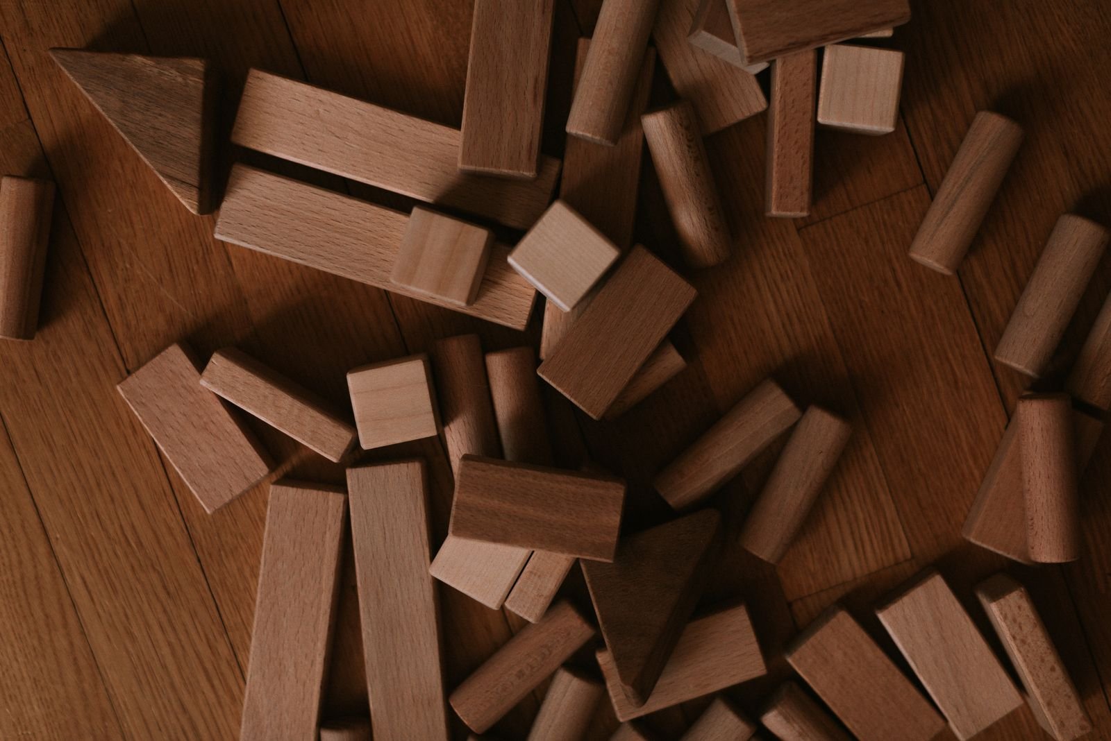 Wooden building blocks scattered on a floor, a reminder that you build an app without coding one small piece at a time