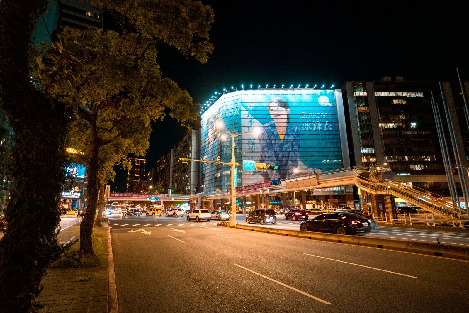 Busy city street at night covered in lighted billboards, a preview of ads arriving inside ChatGPT