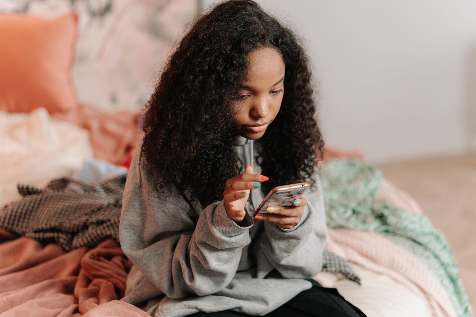 ChatGPT for Teens: What Parents Can Actually Control 1 A teenager sitting on a bed using a phone, the setting where ChatGPT for Teens now applies by default