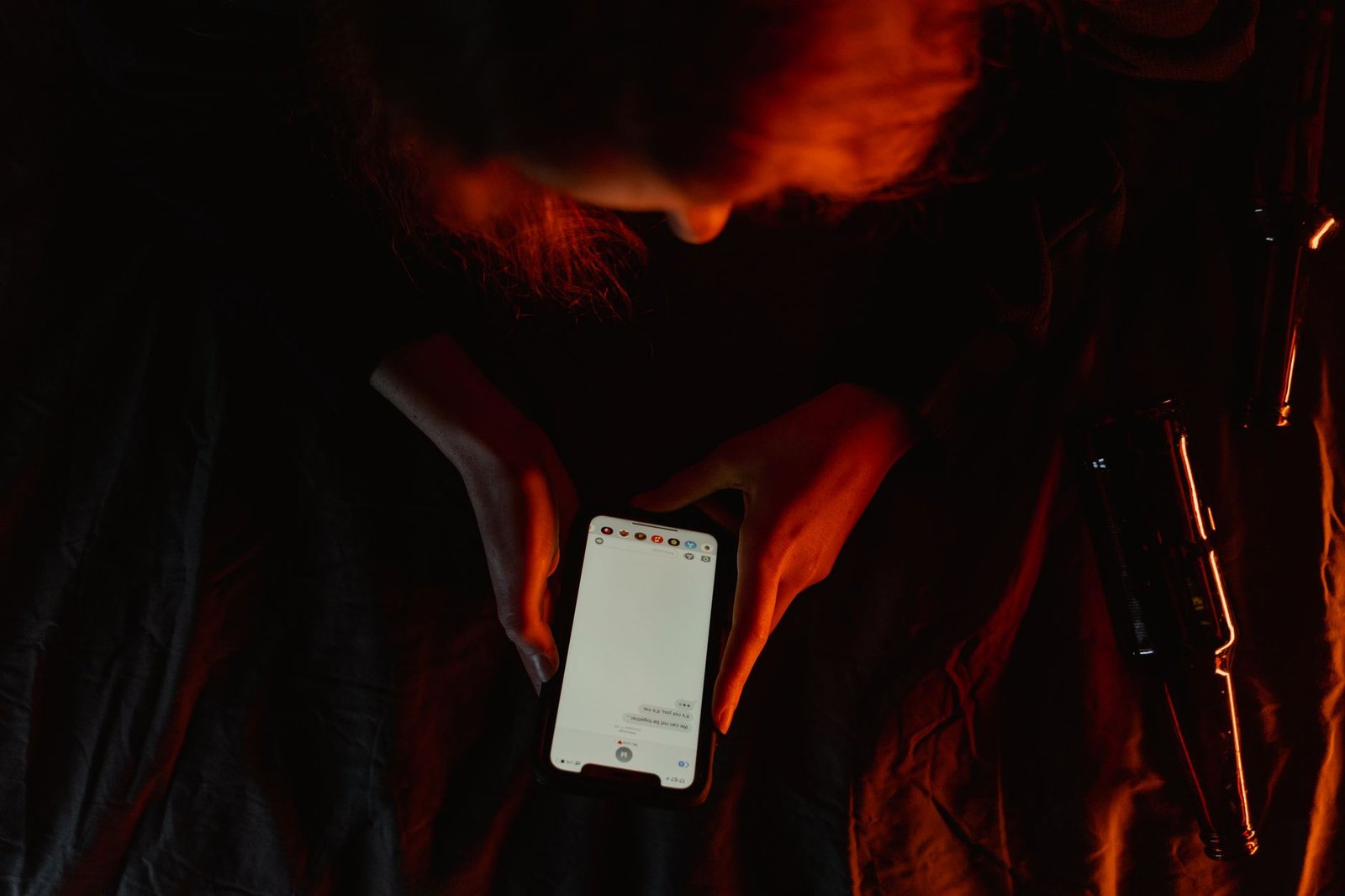 A person studying a video on a phone in dim light, checking whether what they are watching is real