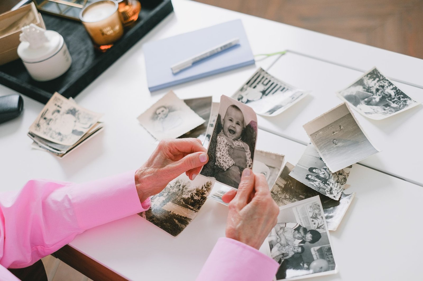 OpenAI Is Shutting Down DALL-E in ChatGPT on August 30 — Here’s What to Do 2 Person sorting through old photos on a table, like saving DALL-E images before the August 30 deadline
