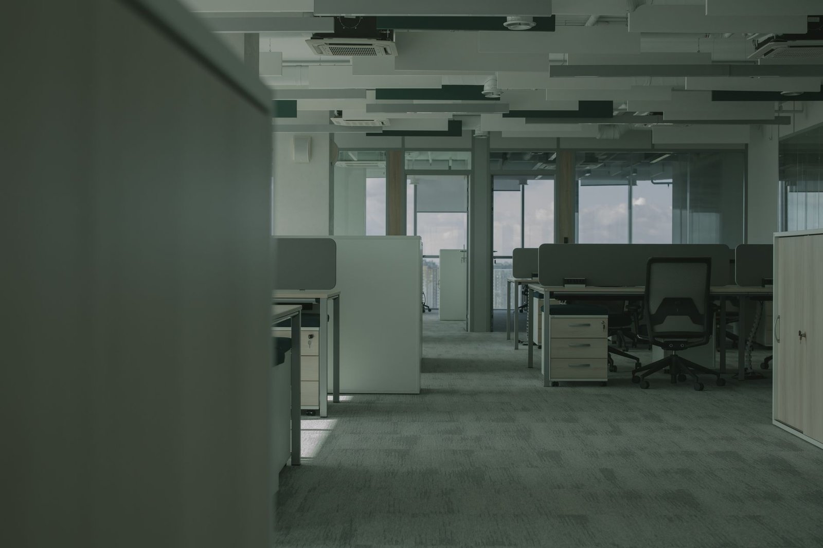 An empty open-plan office with rows of unused desks and chairs