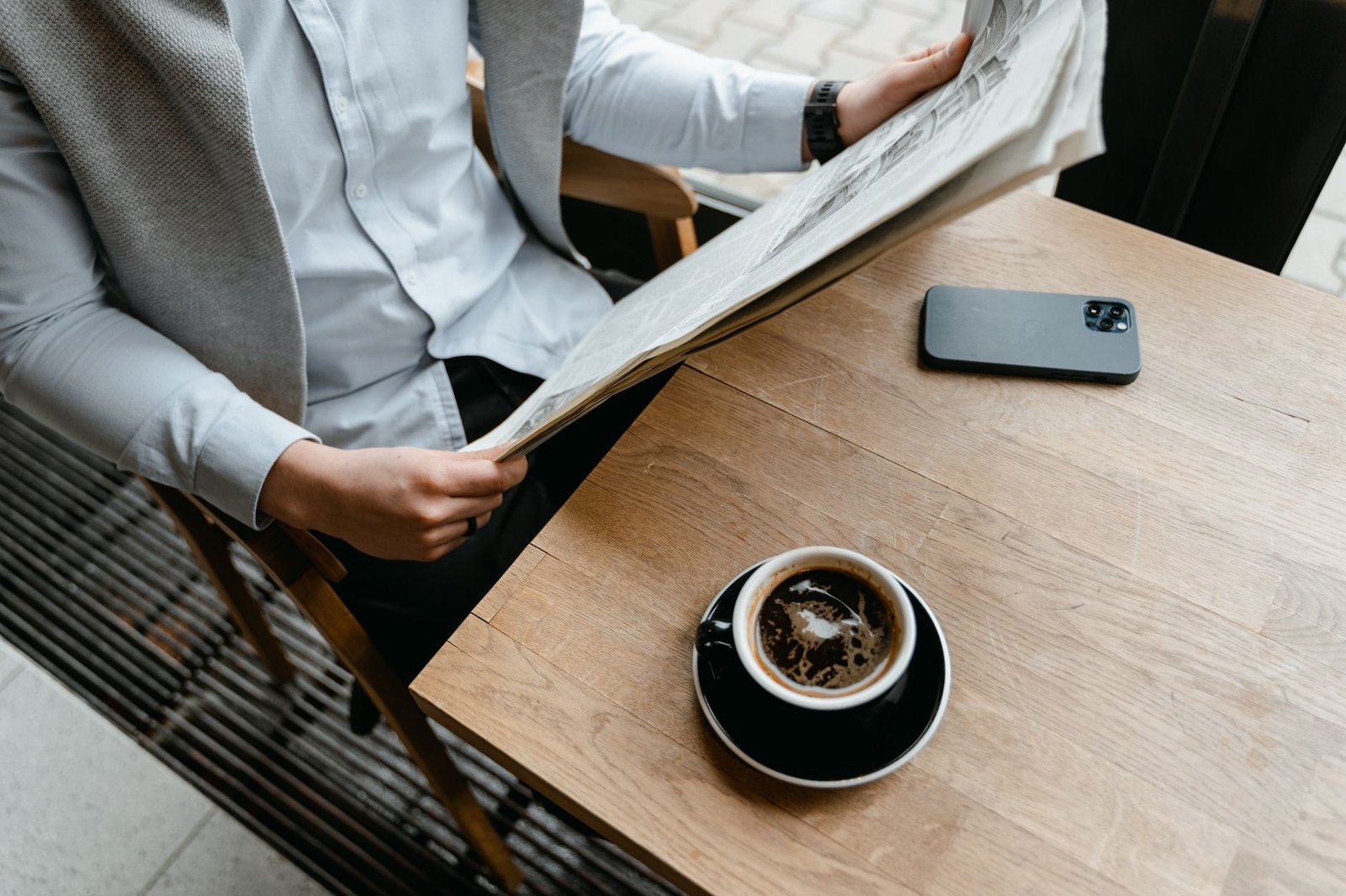 Man reading the news over coffee with his phone beside him, the routine Gemini Daily Brief replaces