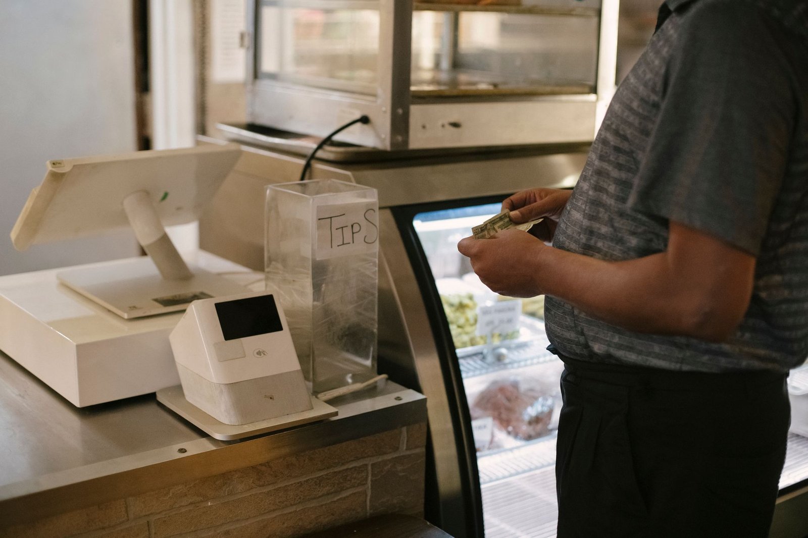 A shopper holding cash at a register, the moment of approval an AI agent should always stop for