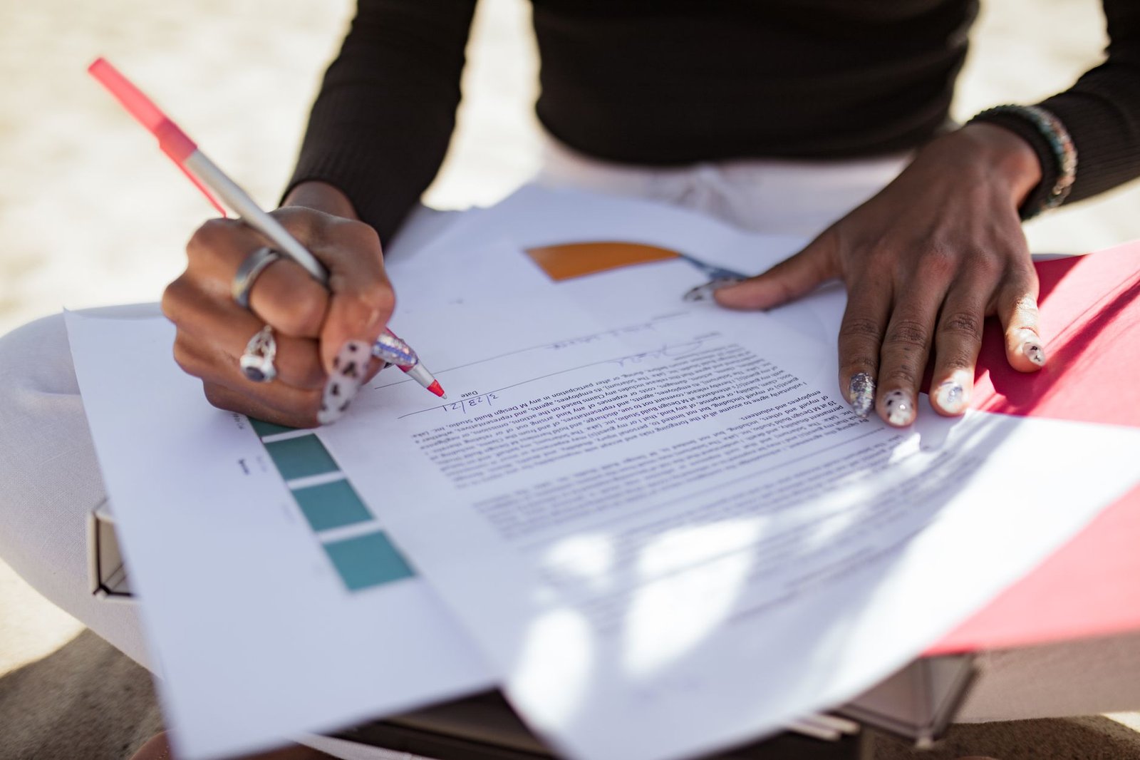 A hand marking corrections on a printed page with a red pen