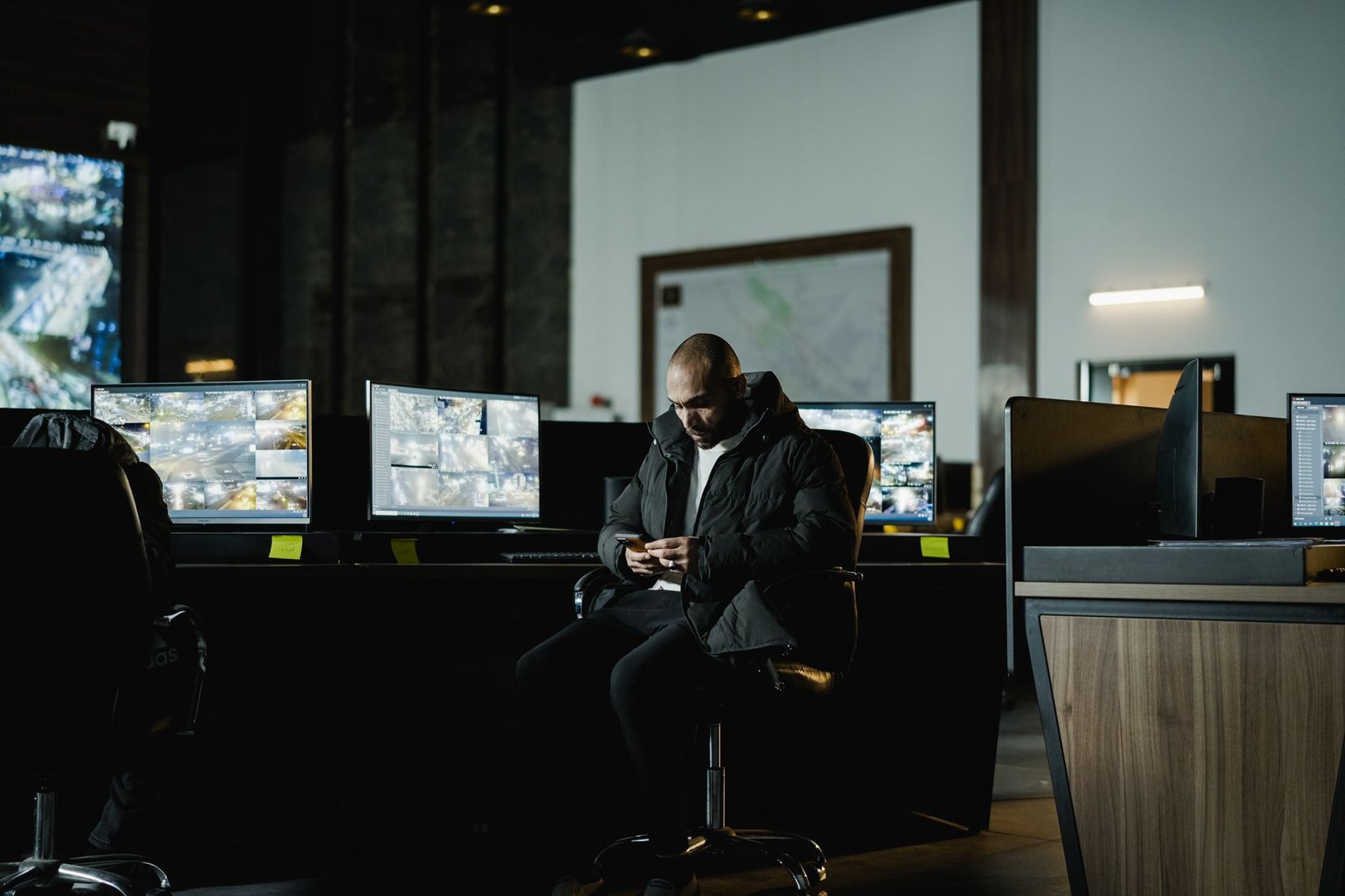 A security officer watching multiple screens in a dim control room, one of the AI cybersecurity jobs in demand