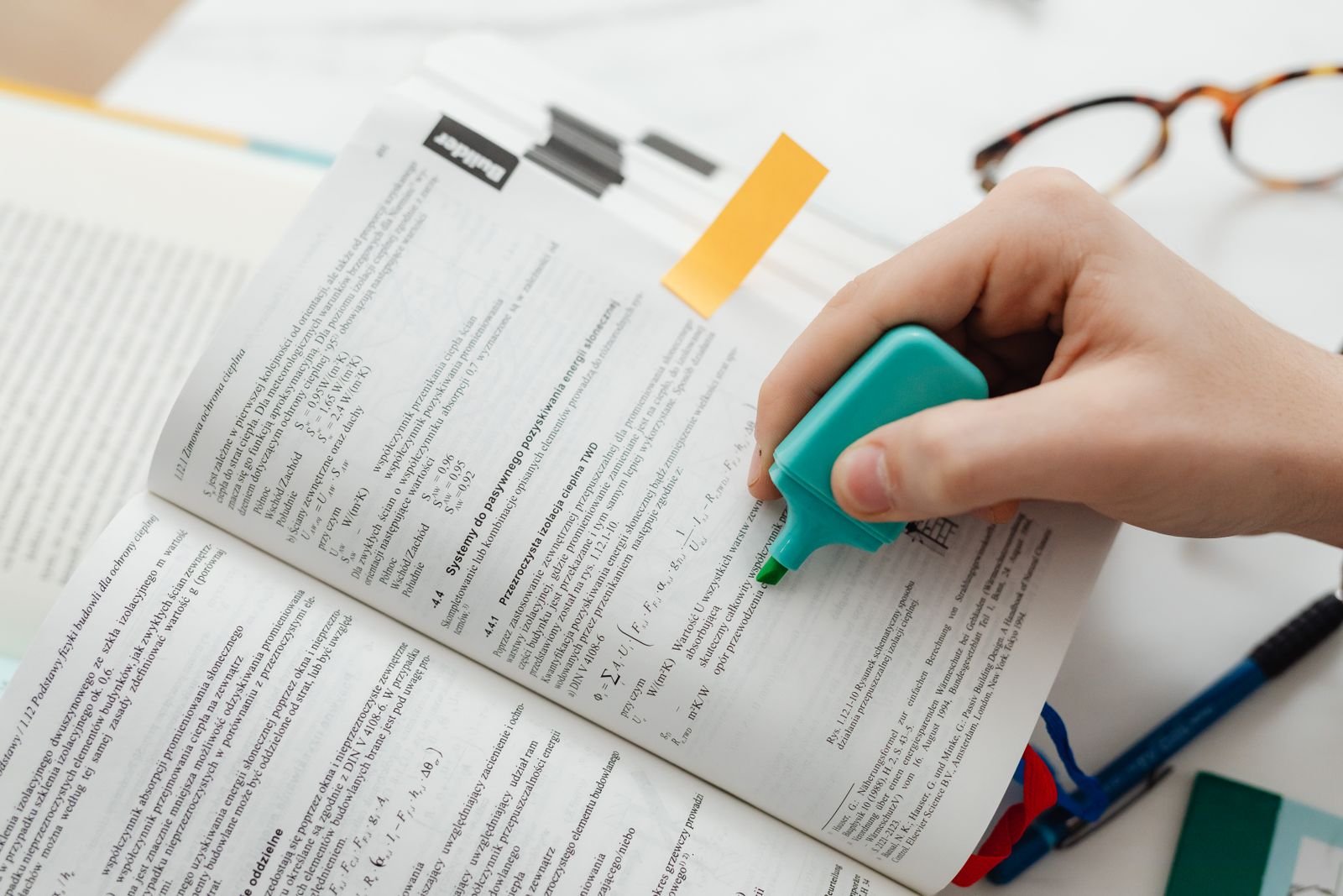 Close-up of a hand highlighting key information in a textbook while studying