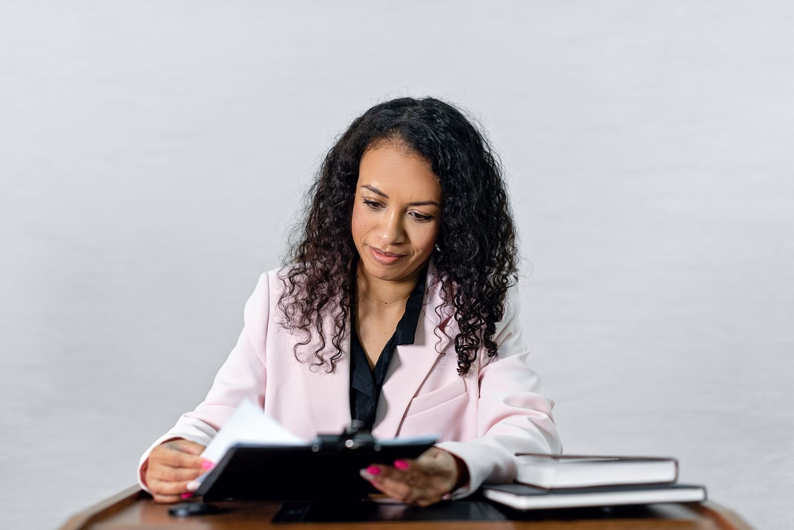 A woman at a desk reading through a stack of paper documents, the way paid reviewers read real ChatGPT conversations