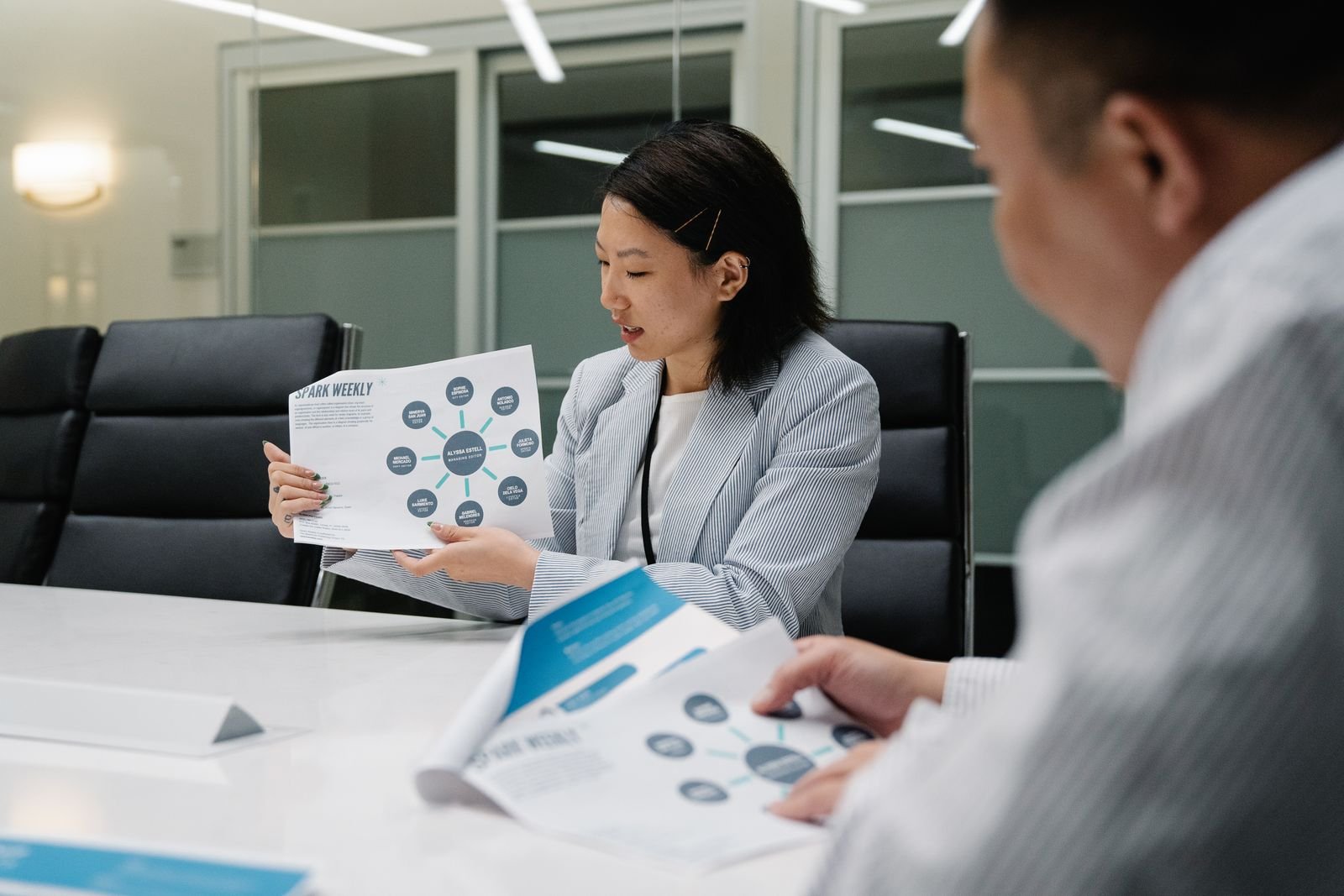 Claude Will Now Write the Doc and the Deck for You, and You Can Open Them in Word or PowerPoint 3 Colleagues in a conference room reading printed reports together, the kind of document Claude Docs is built to draft