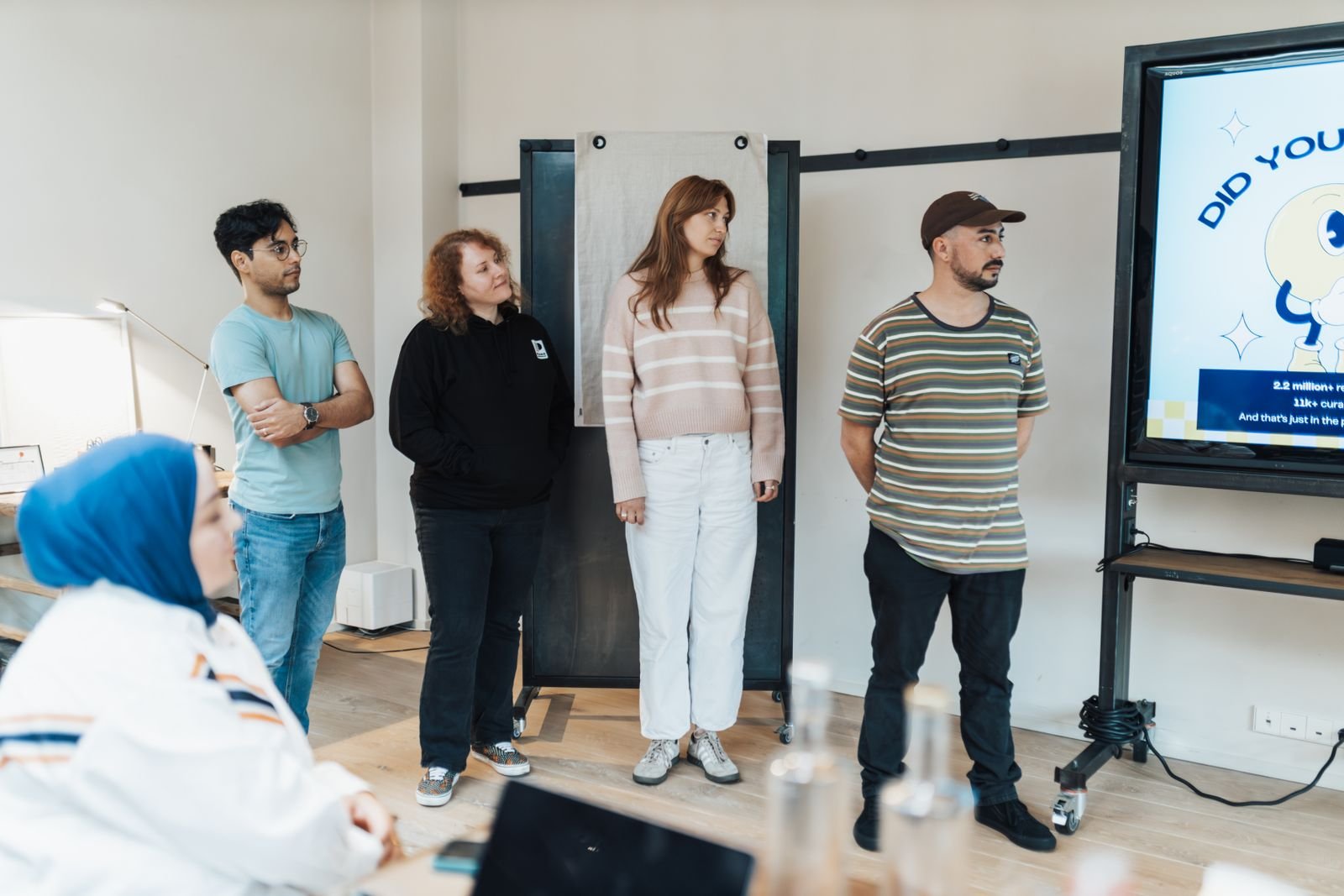 Claude Will Now Write the Doc and the Deck for You, and You Can Open Them in Word or PowerPoint 4 A group of adults in a bright office watching a slide presentation