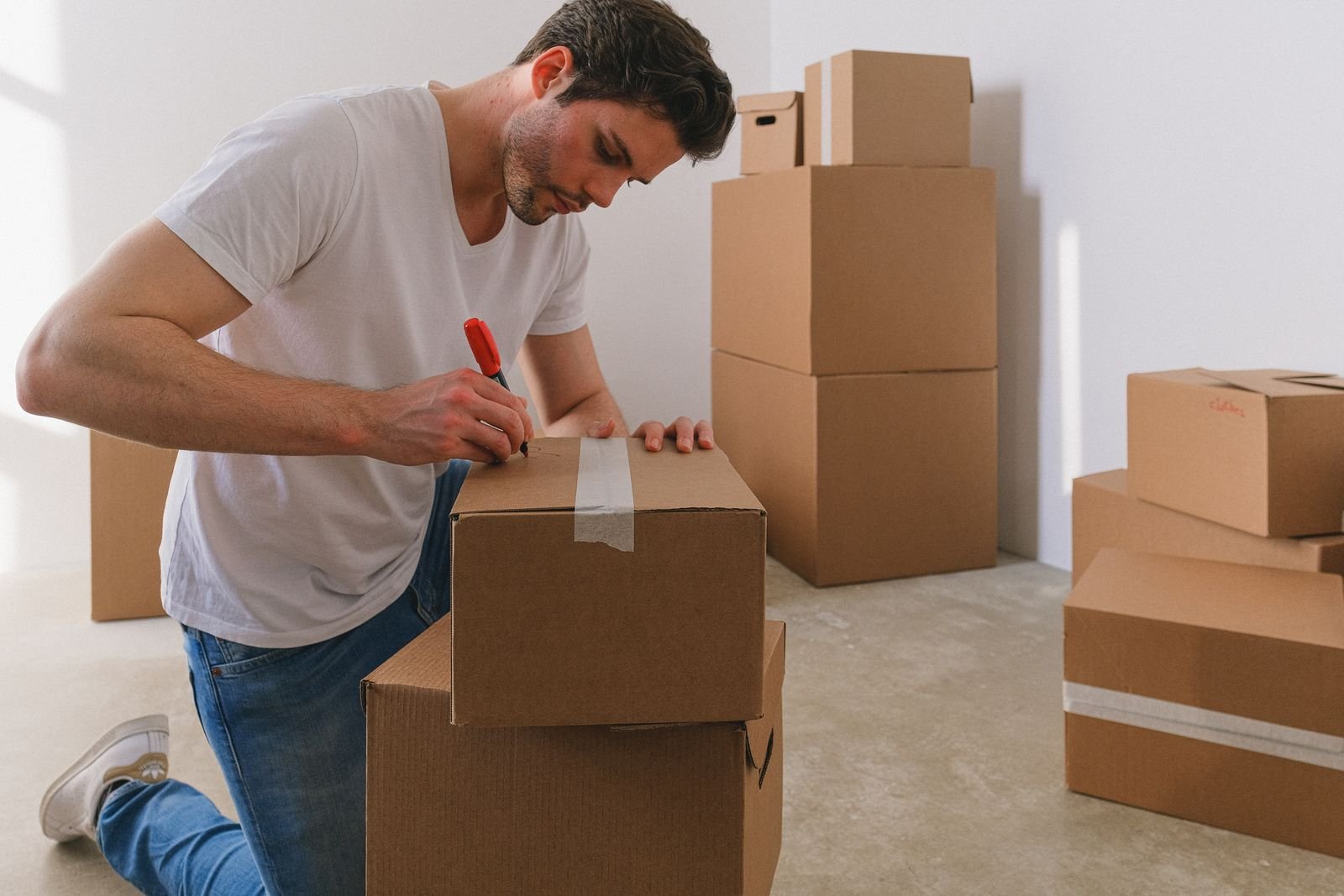 A man labels cardboard boxes before a move, deciding what comes along