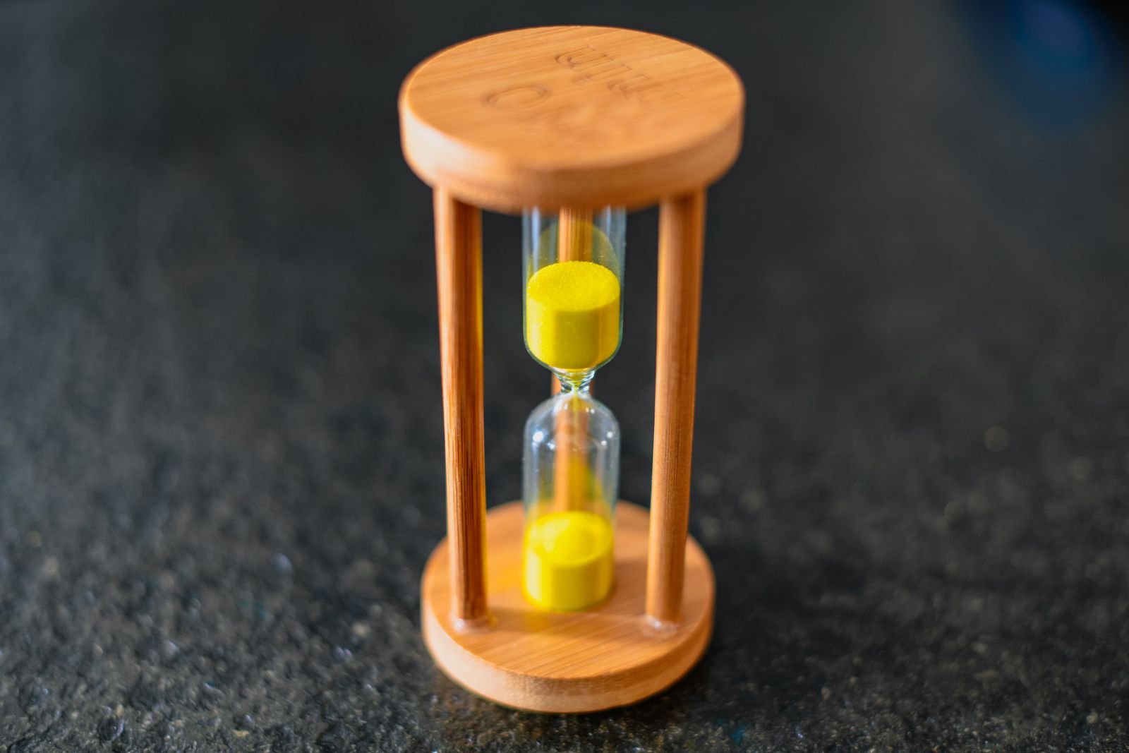 iOS 27 Is Draining iPhone Batteries. Here's What Apple Actually Says. 2 Wooden hourglass with yellow sand, standing in for how long iOS 27 battery drain lasts
