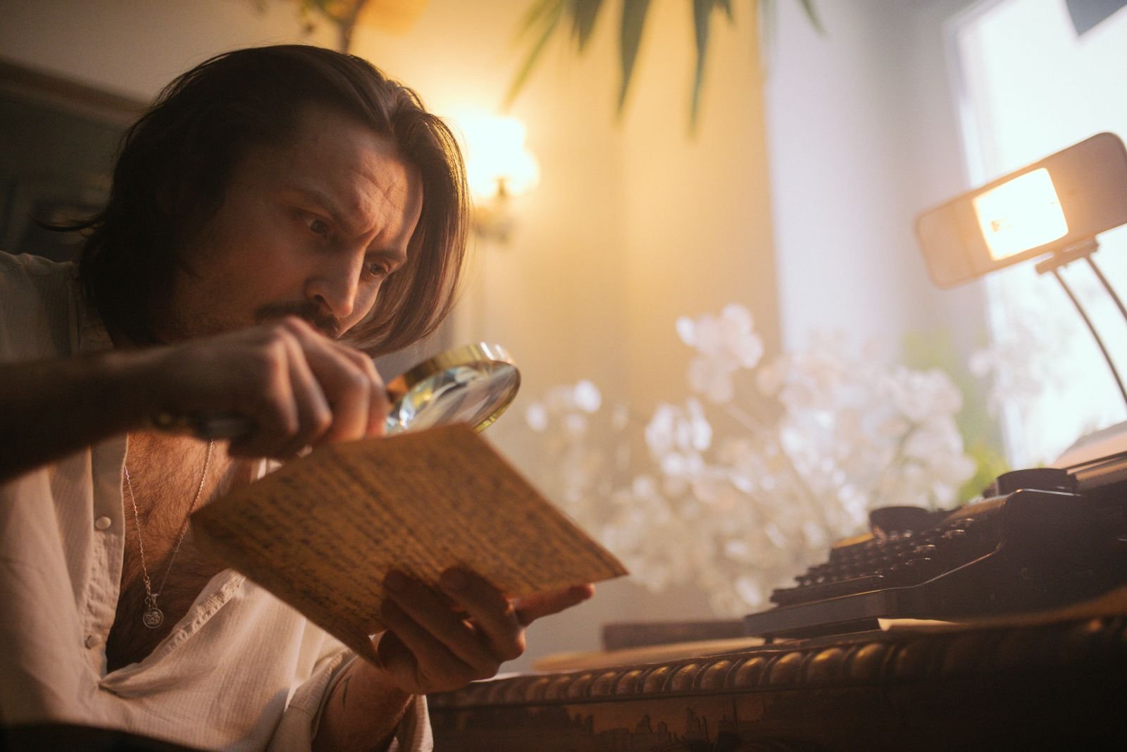 A man examines a document with a magnifying glass at a desk under warm light, a stand-in for the contractors reading ChatGPT conversations