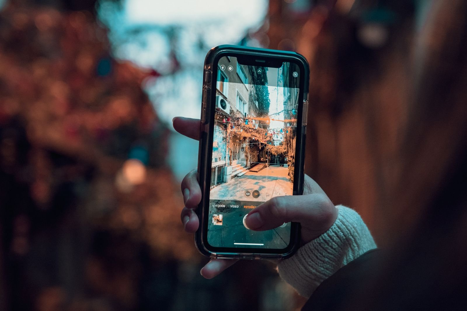 Google's Search Live Now Switches Languages Mid-Conversation. Here's How to Try It. 2 A hand holding a smartphone up to a city street, the way you would to start Search Live in the Google app