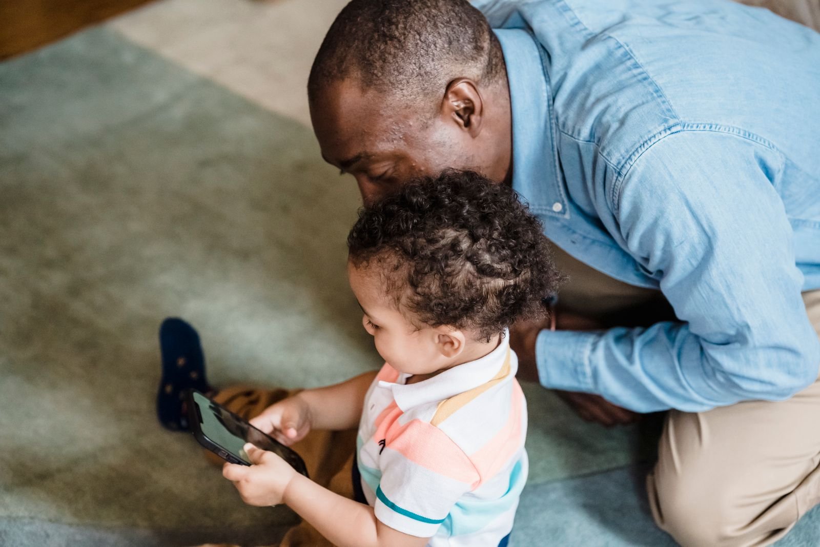 How to Turn Off Siri AI and Get Siri Classic Back in iOS 27 3 A father and son looking at a smartphone together on the couch, like a parent setting Screen Time limits for Siri