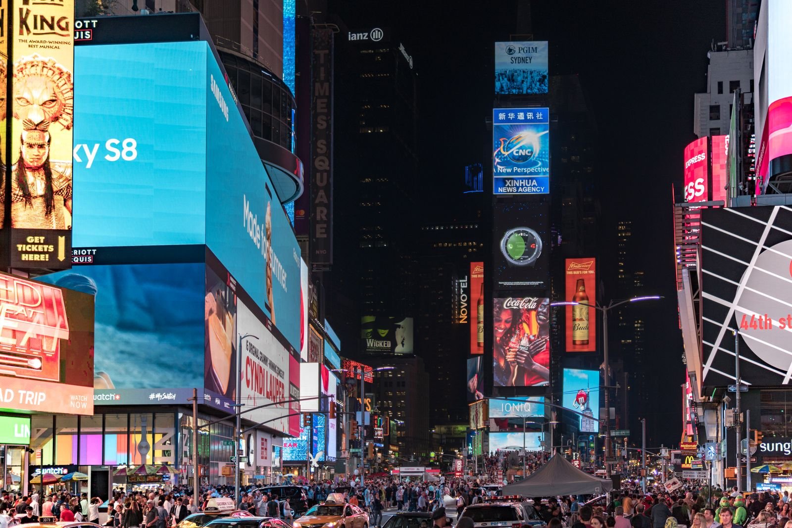 Times Square billboards at night above a crowd, a stand-in for the ads Instagram Plus subscribers still see