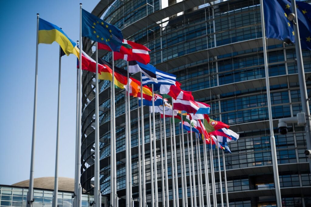 EU member flags outside the European Parliament, where the AI Act rules behind the ChatGPT watermark were written