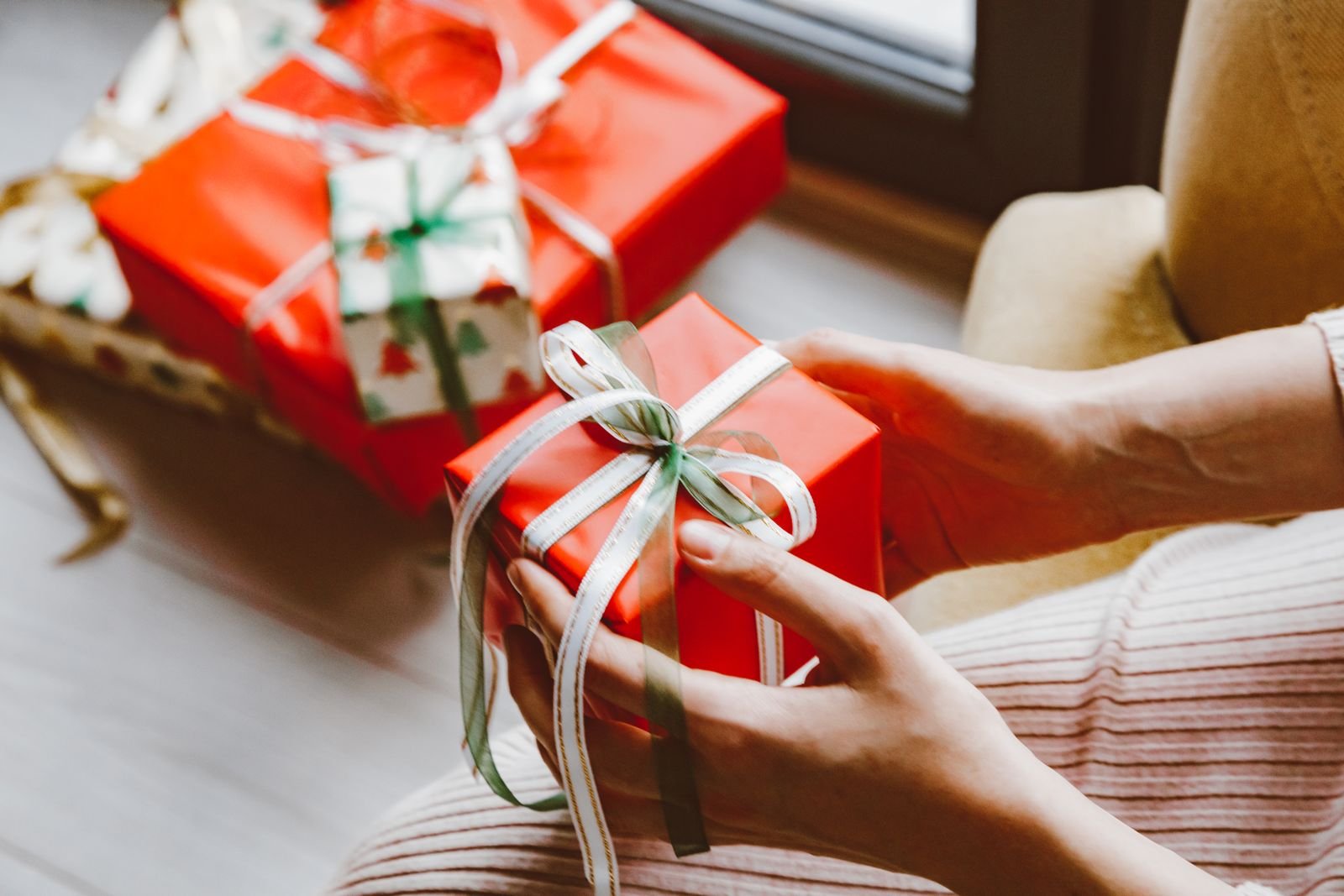 Hands holding a small wrapped gift tied with ribbon